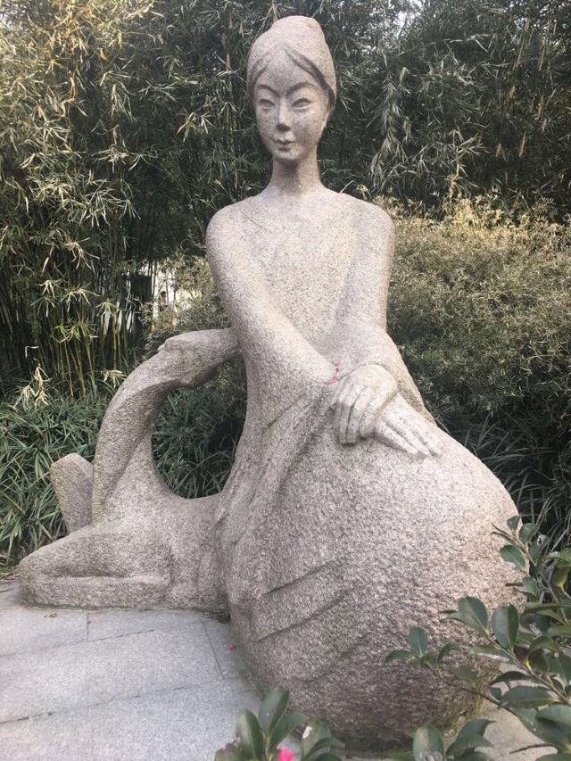 雕像中的美女端庄文雅,旁边的鹿在仰头观望.