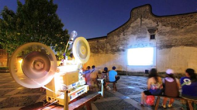 露天电影的放映场地位于西栅的大戏院广场,坐在露天的长条凳上看一场